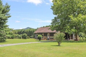 A two-story house with a front porch, surrounded by a well-maintained lawn and trees. - Sycamore Shade: 151 House, HOT TUB, Mountain Views (Afton)