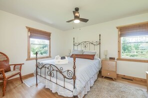 A bedroom with a bed, a wooden chair, a nightstand, and a ceiling fan.