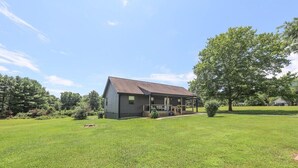 A single-story house with a porch, surrounded by a well-maintained lawn and trees.