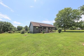 A single-story house with a porch, surrounded by a well-maintained lawn and trees. - Sycamore Shade: 151 House, HOT TUB, Mountain Views (Afton)