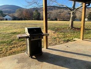 A portable grill on a concrete patio with a view of a grassy field and a house in the background. - Sycamore Shade: 151 House, HOT TUB, Mountain Views (Afton)