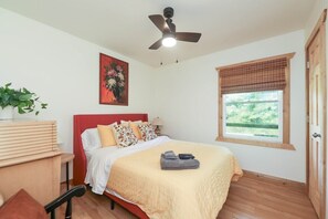 A bedroom with a bed, a ceiling fan, a window with blinds, a painting on the wall, and a plant. - Sycamore Shade: 151 House, HOT TUB, Mountain Views (Afton)