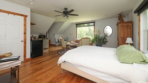 Ein Schlafzimmer mit einem großen Bett, einem Deckenventilator, einem Esstisch und einer Küche im Hintergrund.