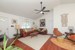 A living room with a ceiling fan, two sofas, a coffee table, and a patterned rug. - Blue Rivers Cottage and Loft (Afton)