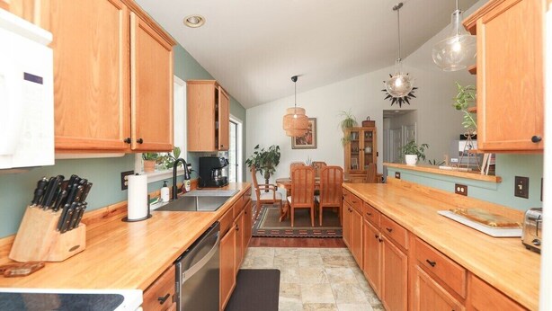 A kitchen with wooden cabinets, a dining area with chairs, and a coffee maker. - Blue Rivers Cottage and Loft (Afton)