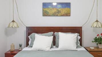 Une chambre à coucher avec une tête de lit en bois, un lit avec une literie blanche et grise, un tableau au-dessus du lit et deux lampes de chevet.