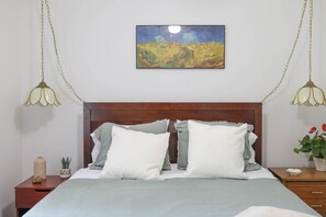 A bedroom with a wooden headboard, a bed with white and grey bedding, a painting above the bed, and two bedside lamps. - Blue Rivers Cottage with Mountain Views (Afton)