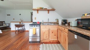 A kitchen with wooden cabinets, a stainless steel refrigerator, a stove, and a microwave.