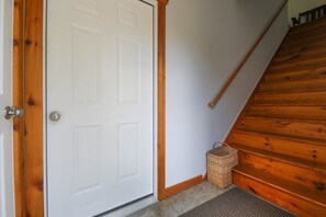Un escalier en bois mène à une porte blanche dotée d’une poignée en métal.