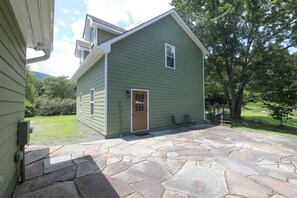 A green single-story house with a stone patio and a small front yard. - Blue Rivers Loft on the Brew Ridge Trail (Afton)