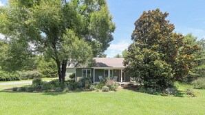 A single-story house with a front porch, surrounded by a well-maintained lawn and mature trees. - Blue Rivers Loft on the Brew Ridge Trail (Afton)
