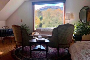Une pièce confortable avec une grande fenêtre, deux fauteuils, une petite table et un canapé.