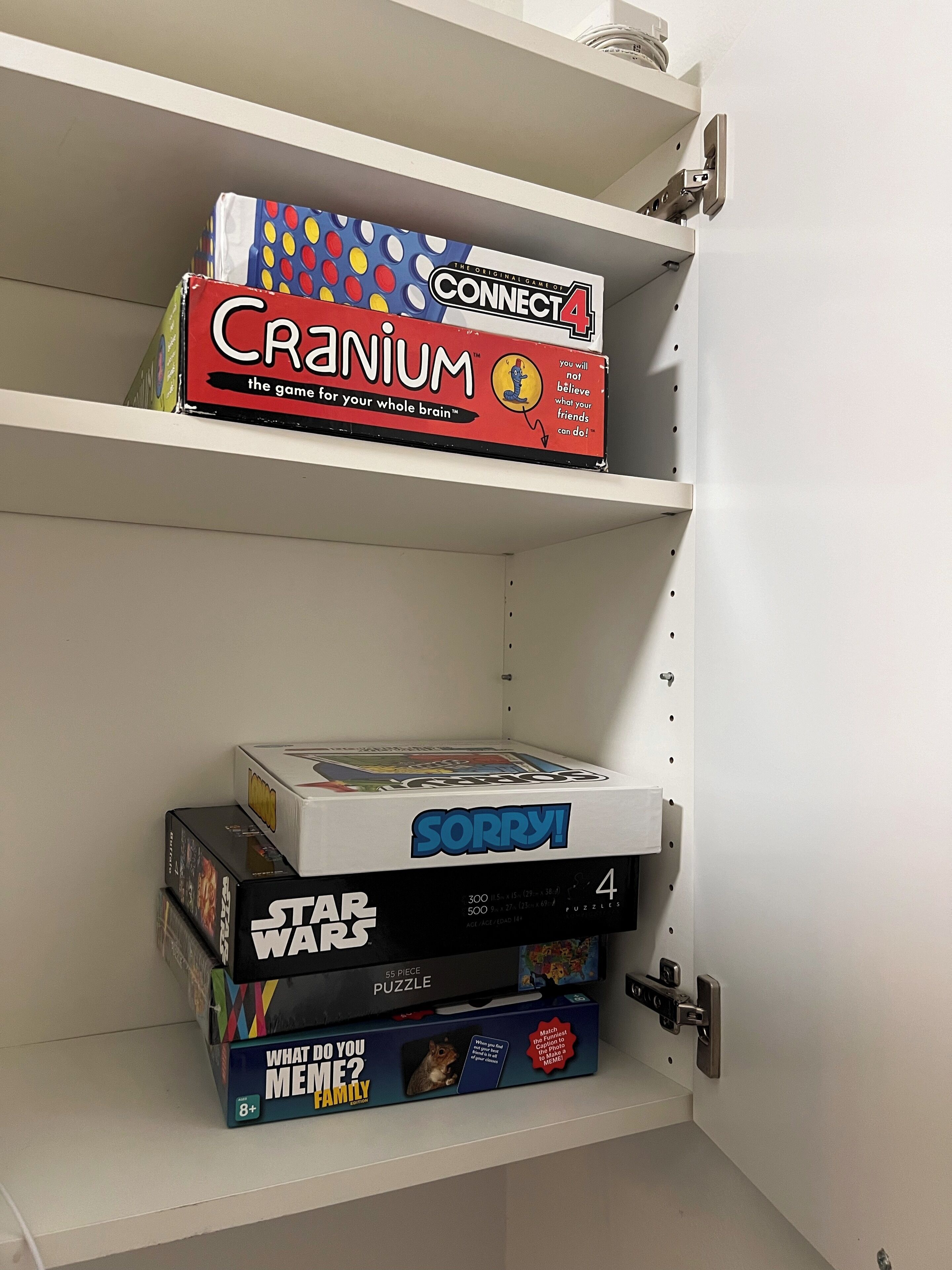 A shelf with three board games: Connect4, Cranium, and Star Wars.