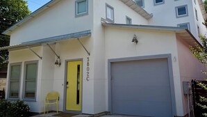 A two-story building with a yellow door, a garage, and a small porch area. - Charming 3-bedroom house in central Austin (Austin)
