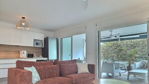 Una sala moderna con sofá, una mesita redonda y una zona de cocina con armarios y un microondas.