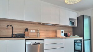 Una cocina moderna con electrodomésticos de acero inoxidable, encimera de madera y armarios blancos.