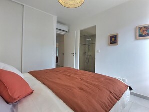 Une chambre à coucher avec un lit, une douche et un mur blanc orné d’un tableau.