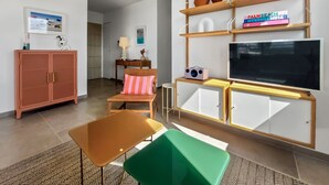 Una sala de estar moderna con televisor, estanterías de madera, un sofá, un armario y una mesita.