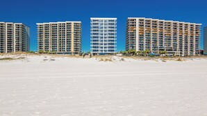 A beachfront hotel with multiple high-rise buildings, a sandy beach in the foreground, and clear blue skies.