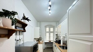Eine schmale Küche mit weißen Schränken, einem Edelstahlbackofen und einer Holz Arbeitsplatte.