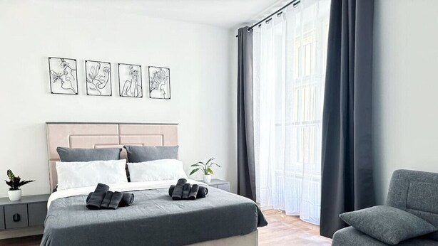 Ein modernes Schlafzimmer mit einem Bett, einem Nachttisch und einem grauen Sessel.