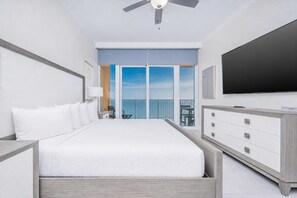 A hotel room with a bed, a TV, a balcony with a view, and a ceiling fan. - Phoenix Gulf Towers Unit 2107 (Orange Beach)