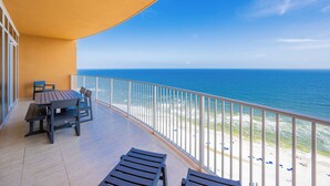 A balcony with a view of the ocean, a table with chairs, and a sunshade. - Phoenix Gulf Towers Unit 2107 (Orange Beach)