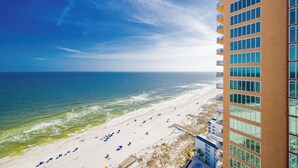 A beach view from a high-rise building with a clear sky, ocean, and beach with umbrellas. - Phoenix Gulf Towers Unit 2107 (Orange Beach)