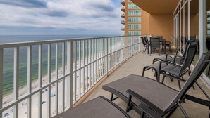 Ein Balkon mit Blick auf Strand und Meer, ausgestattet mit Liegestühlen und einem Tisch.