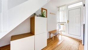 A modern interior with a wooden bench, white cabinets, and a door with a window. - GuestReady - Trendy 2Bed flat in East London (London)