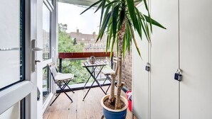 A balcony with a potted plant, a small table, and a chair. - GuestReady - Trendy 2Bed flat in East London (London)