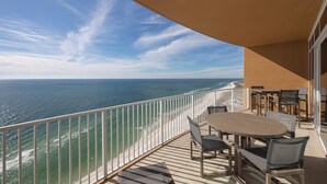 A balcony with a view of the ocean, a wooden table, and chairs. - Phoenix Gulf Towers 2603 (Orange Beach)