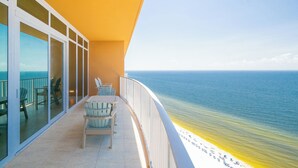 A balcony with a view of the ocean, a table with chairs, and a glass door leading to a terrace. - Phoenix Gulf Towers 2706 (Orange Beach)