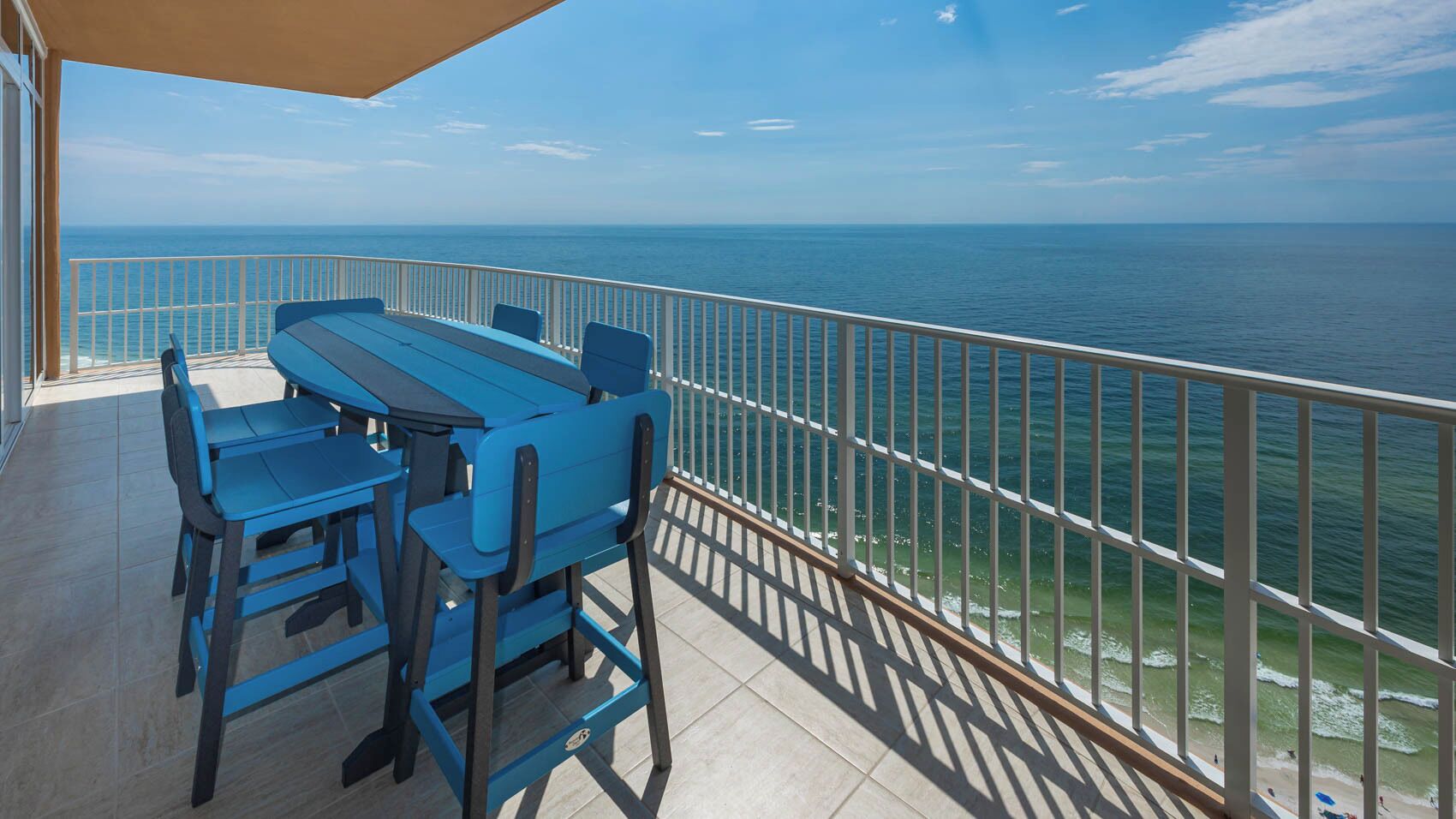 Een balkon met een tafel en stoelen, met uitzicht op zee.
