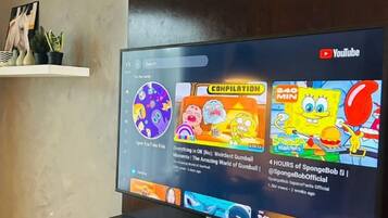 A YouTube interface on a flat-screen TV with a shelf above displaying decorative items.