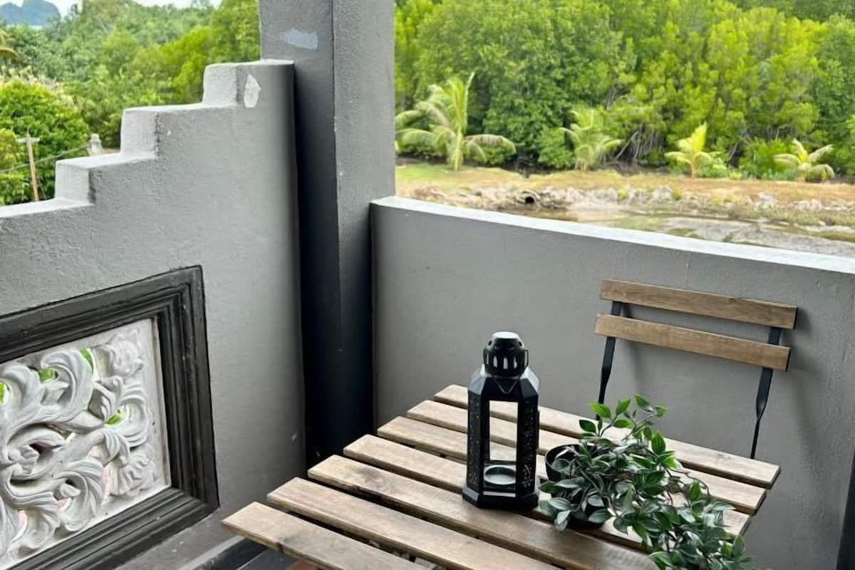 A balcony with a wooden table, a black lantern, and a plant.