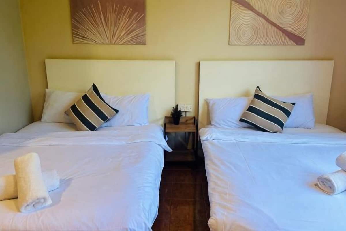 Two twin beds with white linens, striped pillows, and rolled towels.