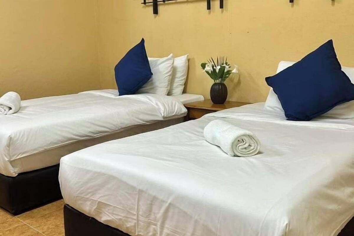 Two twin beds with white linens, blue pillows, and rolled towels.