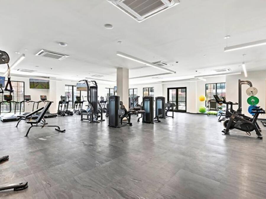 Un gimnasio amplio con diversos equipos de ejercicio, como cintas de correr, máquinas de pesas y una máquina de remo.