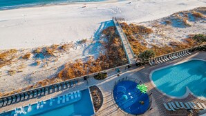 Un resort con una piscina grande, una piscina más pequeña separada y una zona de playa.