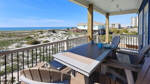 A balcony with a table and chairs overlooking a beach and ocean. - Serene Gulf-front Retreat in Fort Morgan (Gulf Shores)