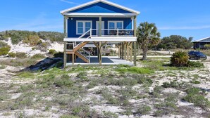 A two-story beach house with a balcony and a staircase leading to the upper floor. - Serene Gulf-front Retreat in Fort Morgan (Gulf Shores)