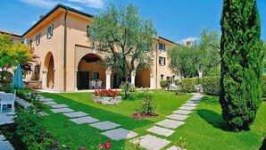 A building with a courtyard, stone pathway, and greenery. - Residence La Filanda in Costermano With Pool (Costermano sul Garda)