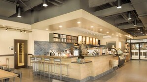 Un café moderno con barra, asientos y una máquina de café.