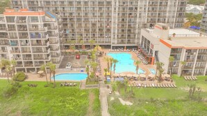 Un hotel con varios balcones, una piscina central y una zona ajardinada.