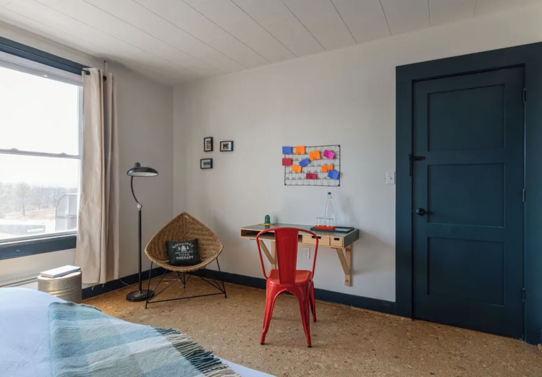 A room with a bed, a desk, a chair, a lamp, a door, and a window.