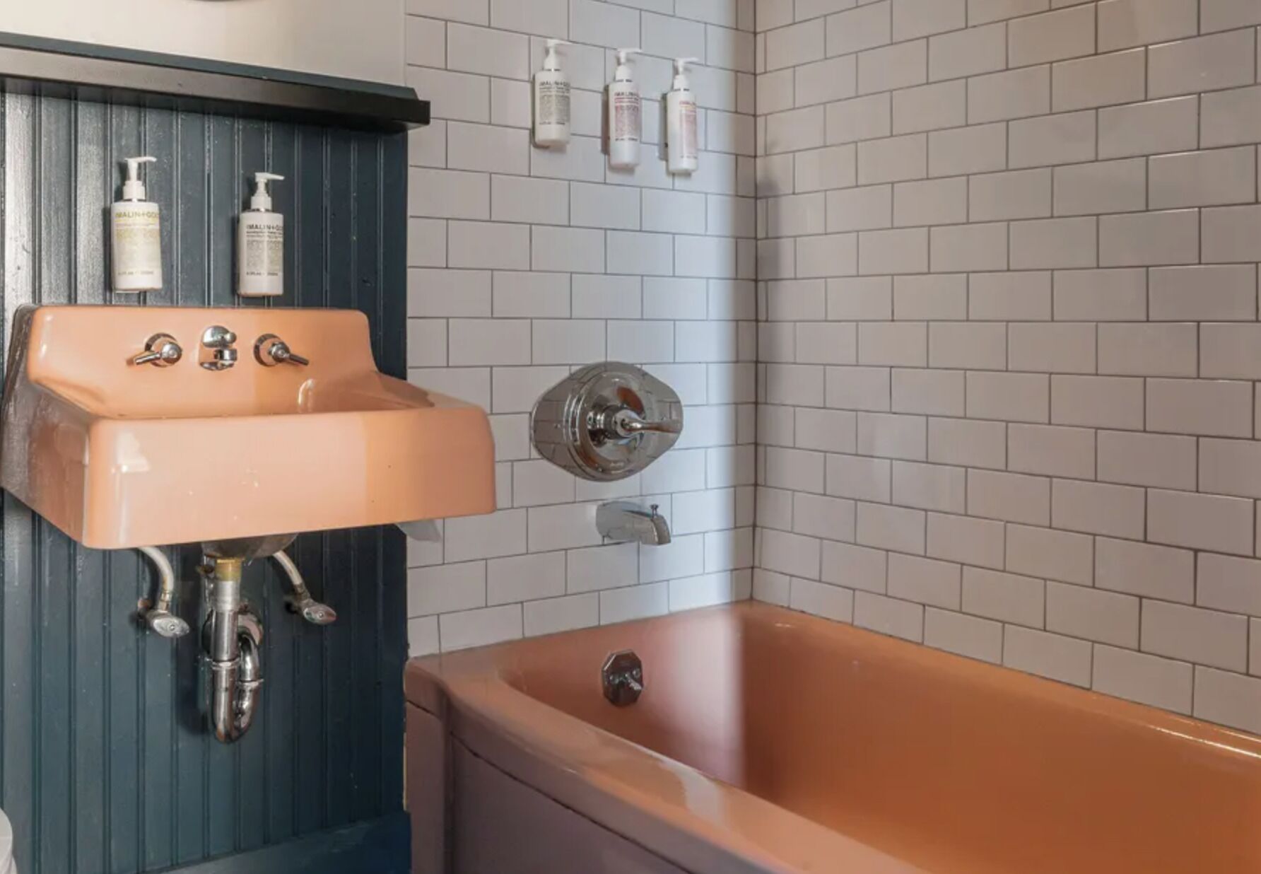 A bathroom with a sink, a bathtub, and toiletries on the wall.