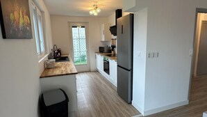 A modern kitchen with a wooden countertop, stainless steel appliances, and a view of the outdoors through a glass door. - Villa-Iska-Calme-Piscine-Moderne-Port-Centre-Plages (La Tremblade)