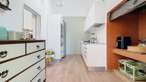 A compact kitchen with white cabinets, a wooden floor, a coffee machine, and a fruit bowl. - Sevenhouse by Atlantic Holiday (Machico)