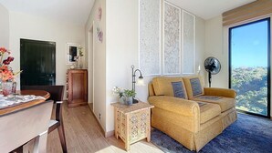 A modern living room with a sofa, a small table, and a dining area with chairs. - Sevenhouse by Atlantic Holiday (Machico)